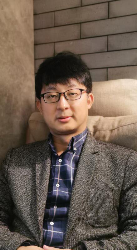 Tibetan man sitting in armchair in front of brick wall