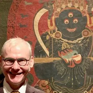 Man standing in front of Tibetan painting